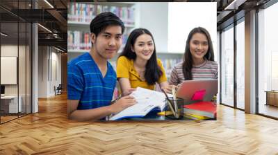 Group Asian  Students Smile and reading book and using notebook for helps to share ideas in the work and project. And also review the book before the exam Wall mural