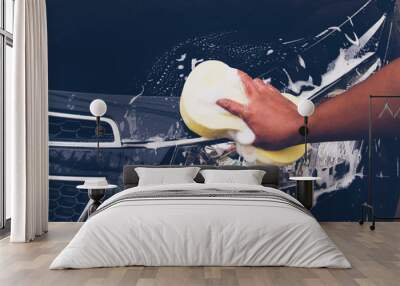 Men use a yellow sponge to wash the car Wall mural