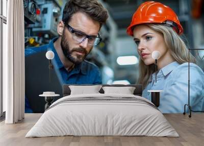 Two engineers a male and a female working together to perform maintenance checks and diagnostics on a relay protection system in an industrial plant using a laptop computer Wall mural