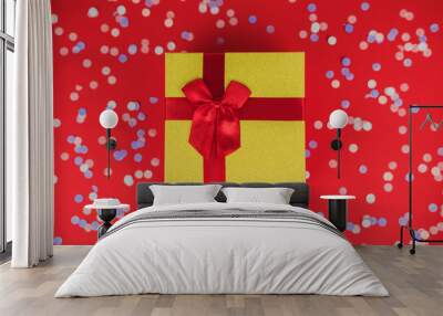 festive christmas and new year background with gold gift box, multicolored confetti on bright red ba Wall mural