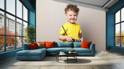 little kid boy 2 years old wearing yellow clothes hold camera isolated on grey wall background, chil Wall mural