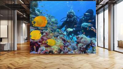 scuba divers couple near beautiful coral reef surrounded with shoal of coral fish and three yellow b Wall mural