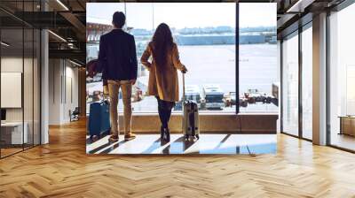 Business couple looking through window at airport departure area Wall mural