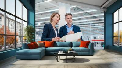 Businessman and businesswoman discussing plan in a factory hall Wall mural