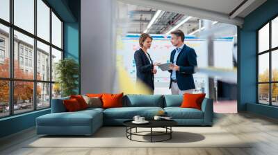 Businessman and businesswoman talking in a factory hall Wall mural