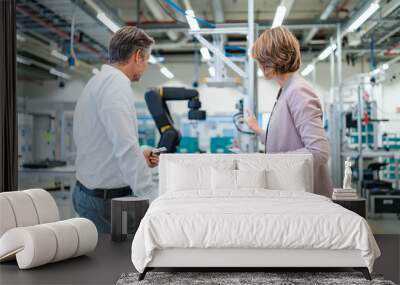 Businessman and businesswoman talking in a modern factory hall Wall mural