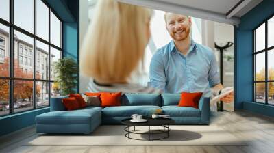 Businessman and woman standing in corridor, talking Wall mural