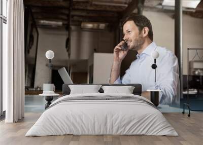 Businessman at desk with laptop and phone Wall mural