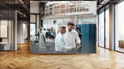 businessman discussing with male colleague over digital tablet in industry Wall mural