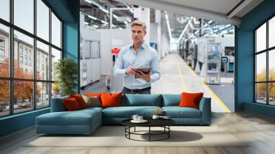 Businessman using tablet in a modern factory Wall mural