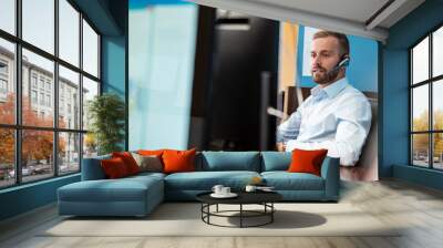 Businessman with headset at desk in office Wall mural