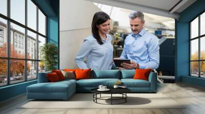 Businessman with tablet and businesswoman having a work meeting in a factory Wall mural