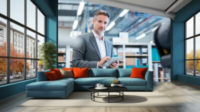 Businessman with tablet in a modern factory hall looking at robot Wall mural