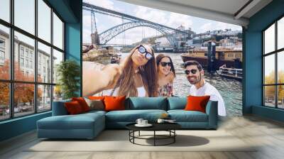 Cheerful young friends taking selfie against Douro River in city, Porto, Portugal Wall mural