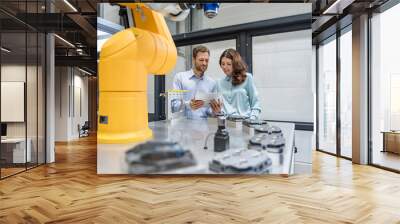 Colleagues in high tech company controlling industrial robots, using digital tablet Wall mural