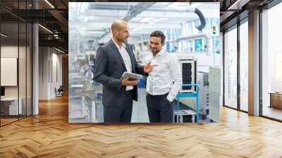 Confident businessman discussing with engineer over digital tablet at factory Wall mural