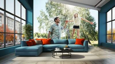 Father helping daughter balancing on a bench in park Wall mural