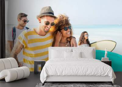 Group of friends walking on the beach, carrying surfboards Wall mural