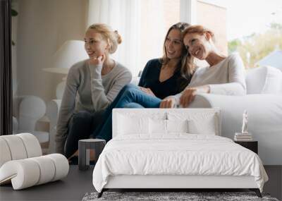 Happy mother with two teenage girls on couch at home Wall mural