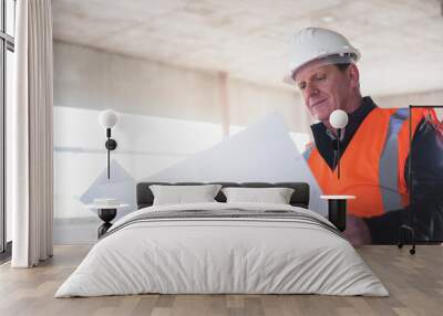 Man with plan wearing safety vest in building under construction Wall mural