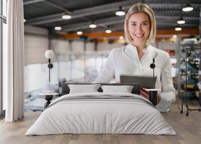 Portrait of smiling young woman using tablet in a factory Wall mural