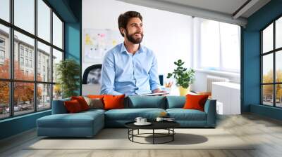 Smiling businessman with headphones using a digital tablet in his office Wall mural