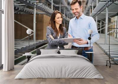 Smiling businesswoman and businessman using tablet in a factory Wall mural