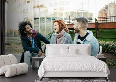 Three happy friends sitting in the city talking Wall mural