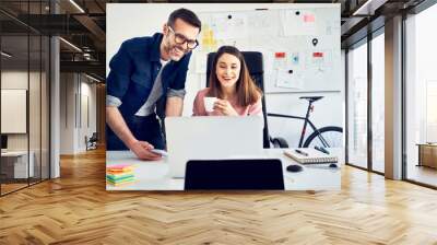 Two colleagues working together on laptop in office Wall mural