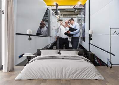 Two men talking among machines in factory shop floor Wall mural