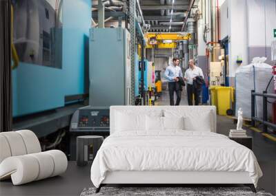 Two men walking and talking in factory shop floor Wall mural