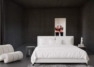 Two men wearing safety vests talking in building under construction Wall mural