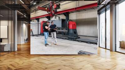 Two men with folder standing on factory shop floor Wall mural