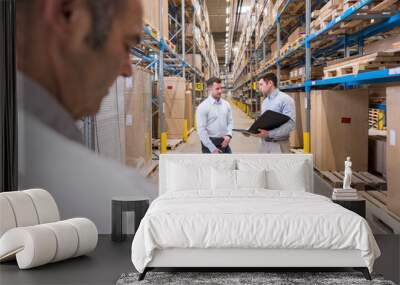 Two men with folder talking in factory warehouse Wall mural