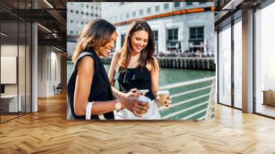 Two women on a bridge with takeaway coffee and cell phone Wall mural