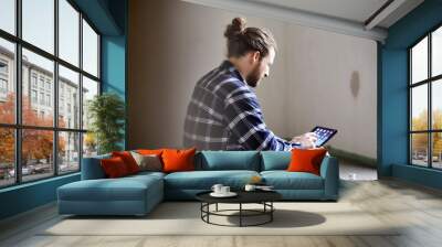 Worker on a construction site sitting on the floor using tablet Wall mural