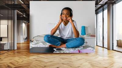 Young girl with cross legged listening to music while sitting at home Wall mural