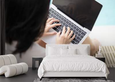 young asian female working beside swimingpool and typing computer labtop for social working every where relax vacation Wall mural