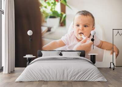 Mother feed her little daughter with a spoon Wall mural