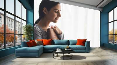 Portrait of a woman with a surgical mask on her face and a bible held tight to her chest Wall mural