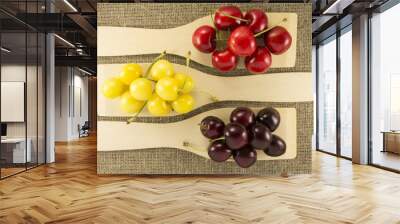 Colorful cherries in a wooden spatula on a natural fabric Wall mural