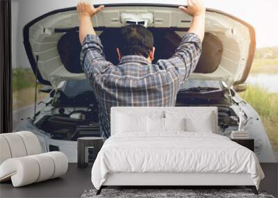 A young man having trouble with his broken car looks frustrated at the engine failure. Wall mural