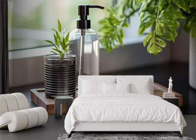 A dark gray clear glass soap bottle on a wooden tray with a plant on the side Wall mural