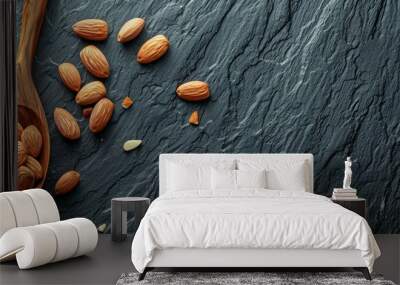 Whole seed of roast Almonds (Prunus dulcis)  in wooden Spoon on Black Slate Background. Have many nutrition and omega-3.Healthy food concept. Top view  and have copy space. Wall mural