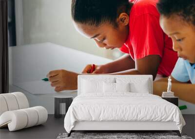 African American kids learning how to draw with crayon on table inside indoors room in natural ambient light Wall mural