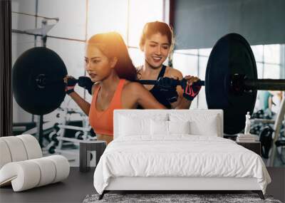 Asian personal trainer coaching a bodybuilding woman to perform the exercise squat with barbell in the fitness gym. Weightlifting and workout training concept Wall mural