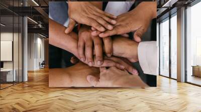 Close up of young business people putting their hands together for unity. Hands stacking over for collaboration and teamwork Wall mural