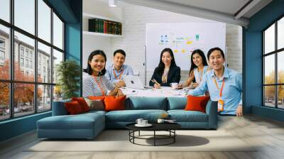 Group portrait of Asian business men and women smiling and looking at camera at company meeting room. Young business people at presentation together. Wall mural