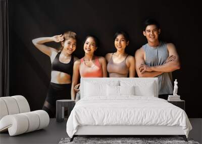 Happy smiling man and women having fun talking in gym. Group of young people relaxing in gym after workout training with black background. Wall mural