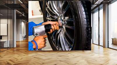 mechanic screwing or unscrewing car wheel at car service garage Wall mural